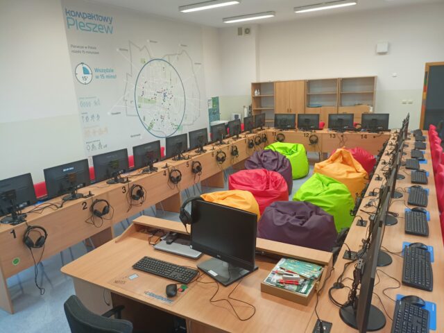 pracownia terminalowo-jezykowa z 24 stanowiskami dla uczniów i dla nauczyciela, w pełni wyposażona, z kolorowymi pufami i mapą kompaktowego Pleszewa na ścianie