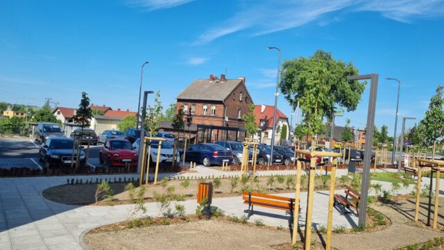 Nowy parking przy stacji kolejowej w Kowalewie otoczony ławkami i zielenią.