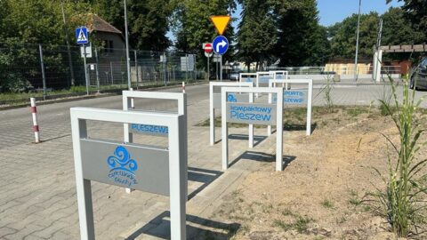 Stojaki na rowery, oznaczone logotypami miasta stojące przy Parku Wodnym "Planty".