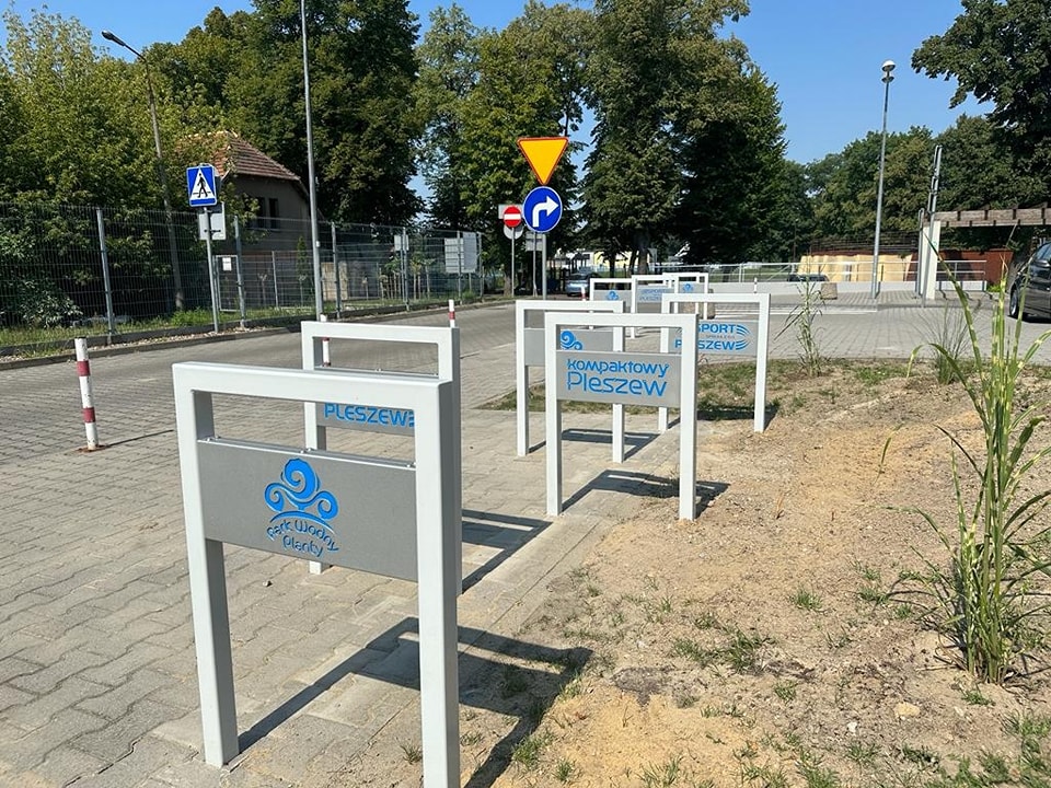 Stojaki na rowery, oznaczone logotypami miasta stojące przy Parku Wodnym "Planty".