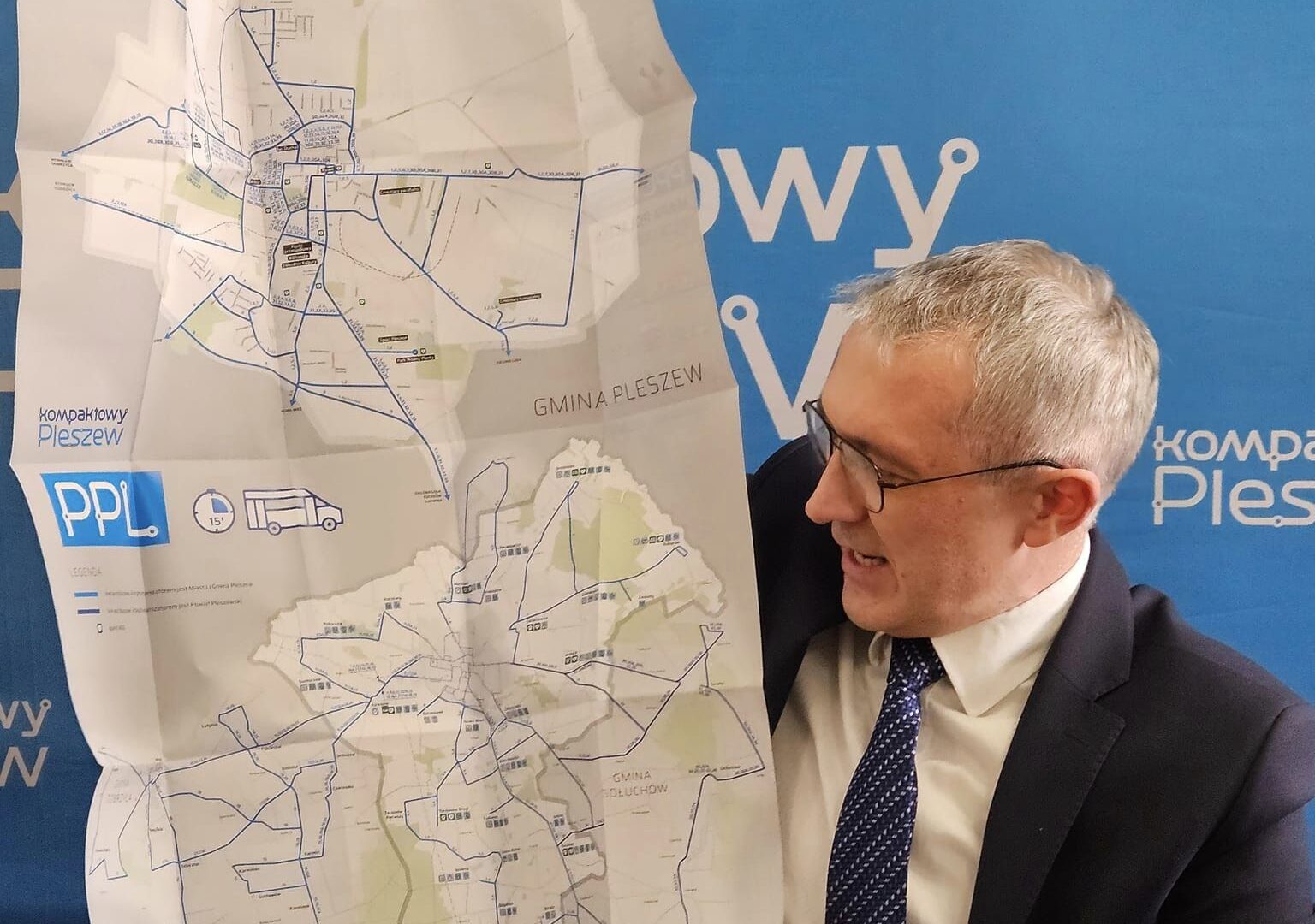 burmistrz MiG Pleszew trzymający mapę z nowymi rozkładami jazdy komunikacji publicznej.
