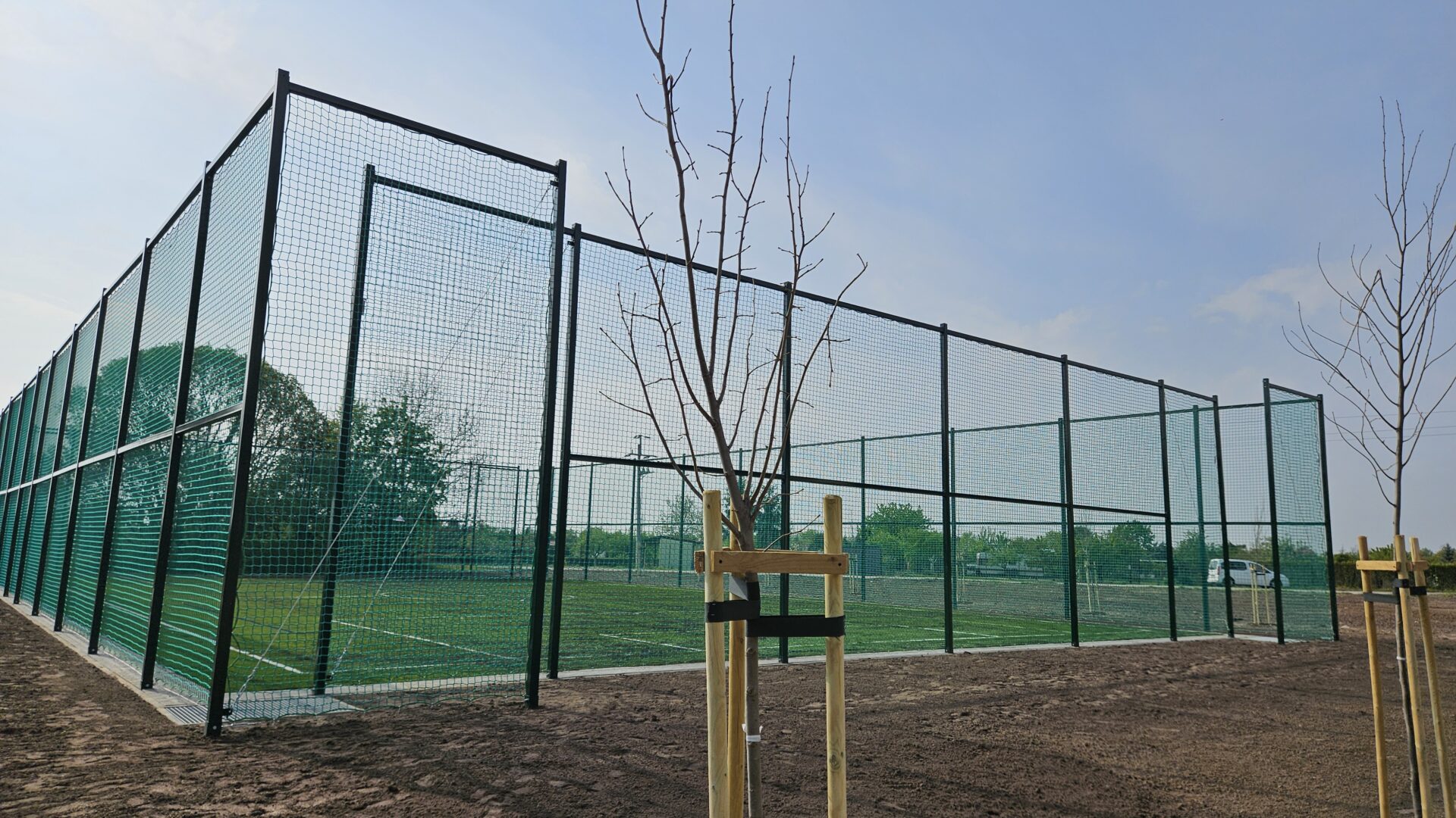 Boisko zewnętrzne otoczone siatką z nowymi nasadzeniami dookoła.