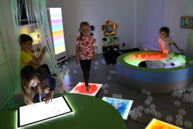 Sala doświadczania świata z urządzeniami stymulującymi zmysły i korzystającymi z nich dziećmi