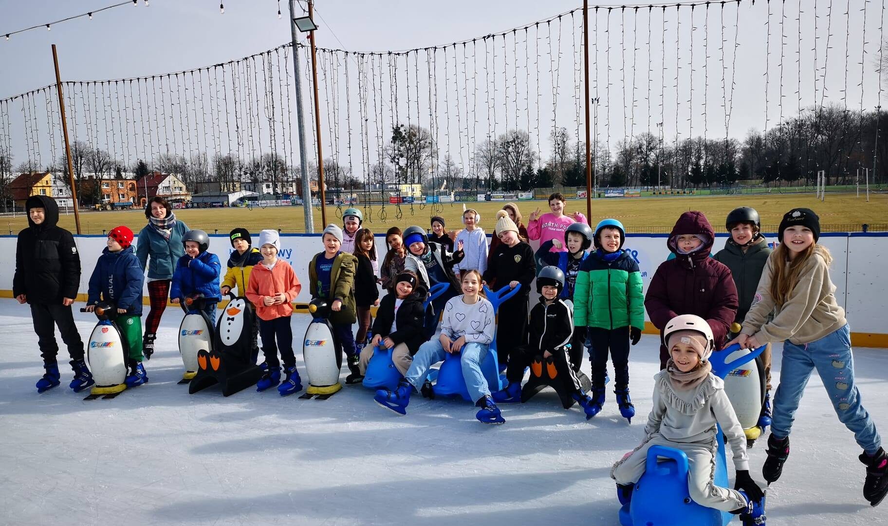 Łyżwiarze na mobilnej tafli pleszewskiego lodowiska na stadionie miejskim podczas grupowej jazdy.